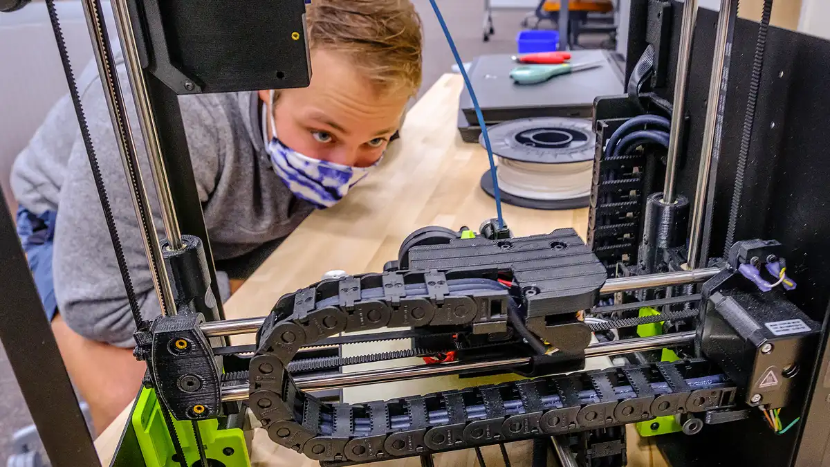 A student looks into a 3D printer.