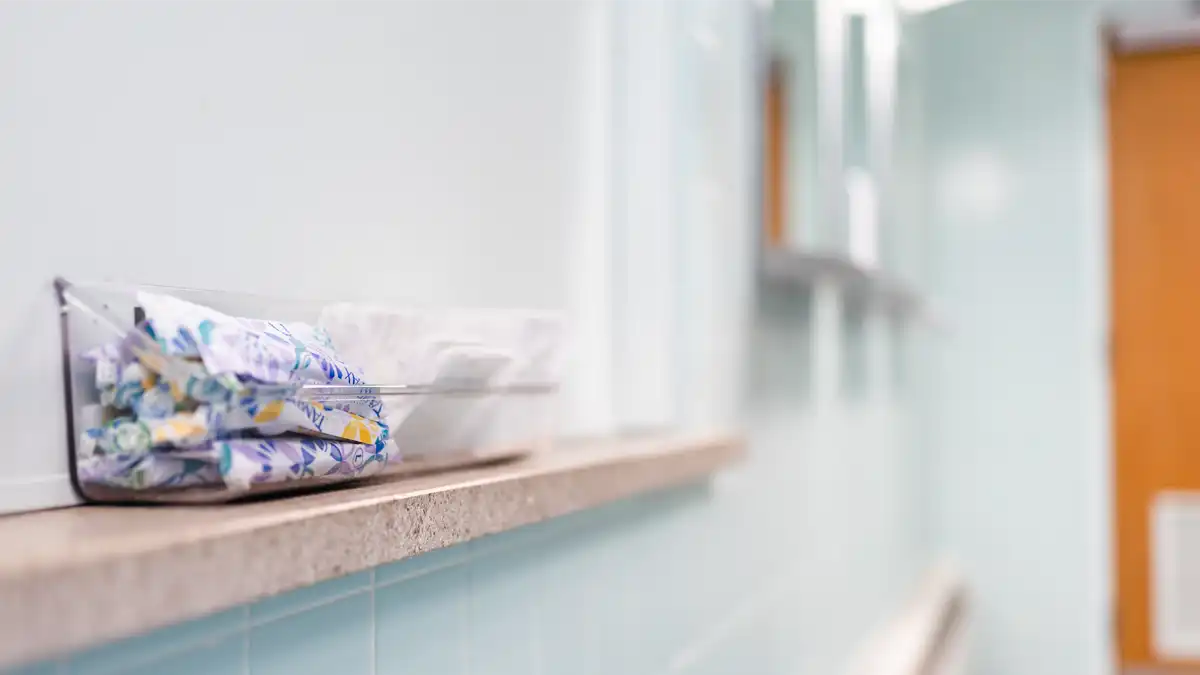 A small container of pads and tampons sits on a ledge in a King Library bathroom.