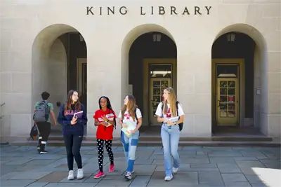 Four students walking out from King Library