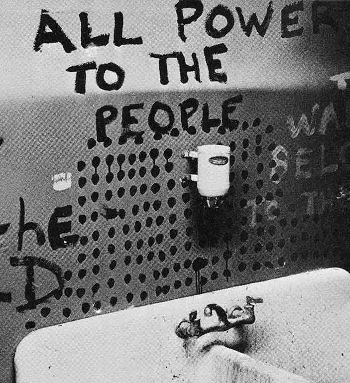 Public bathroom sink with graffiti on the wall