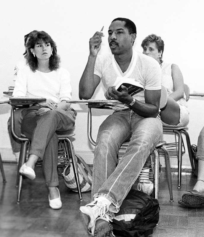 A Black male student at Miami University participates in a classroom discussion while white female students look on